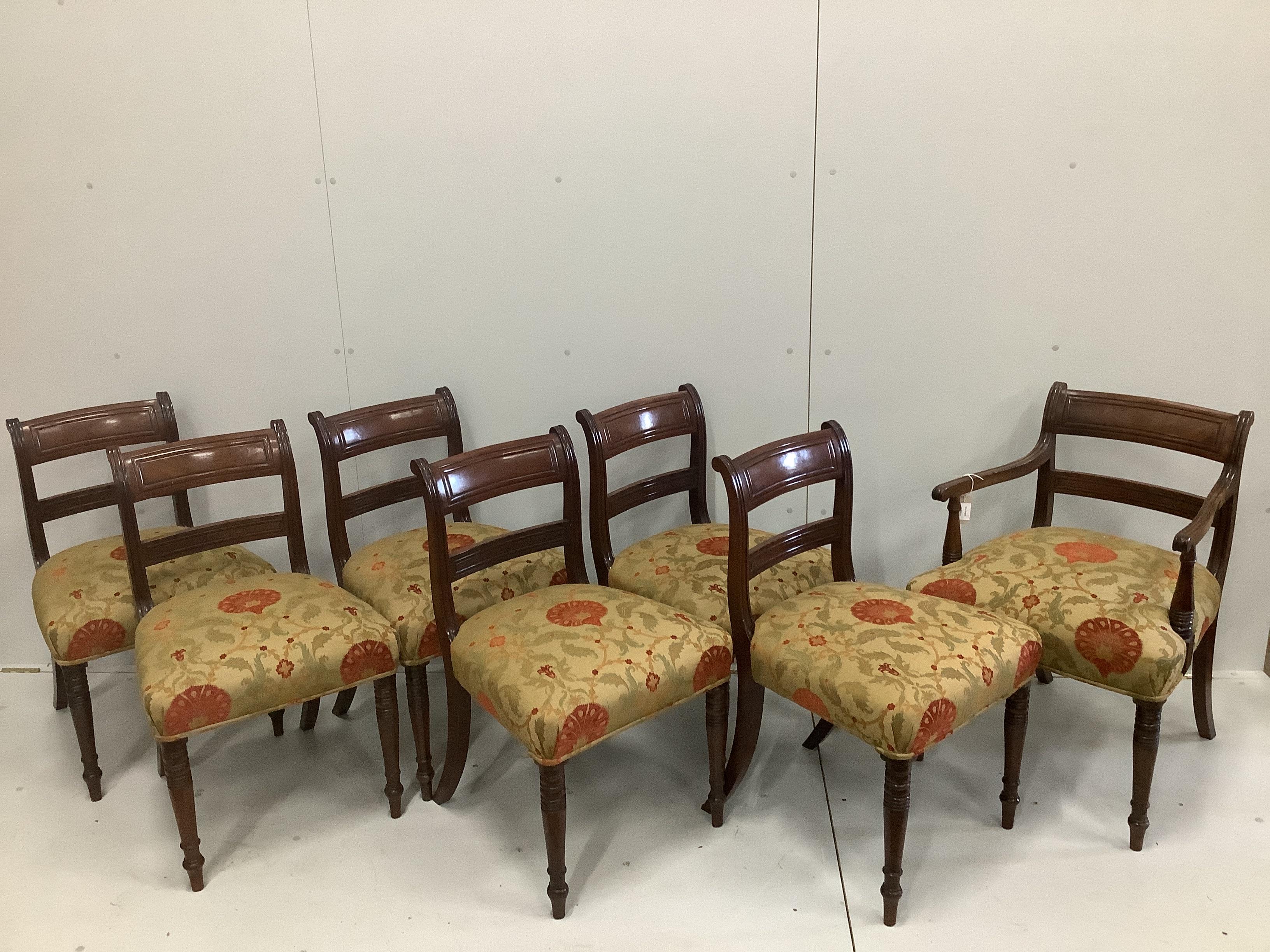 A set of seven Regency mahogany dining chairs with tablet cresting rails, upholstered seats on turned legs, including one carver